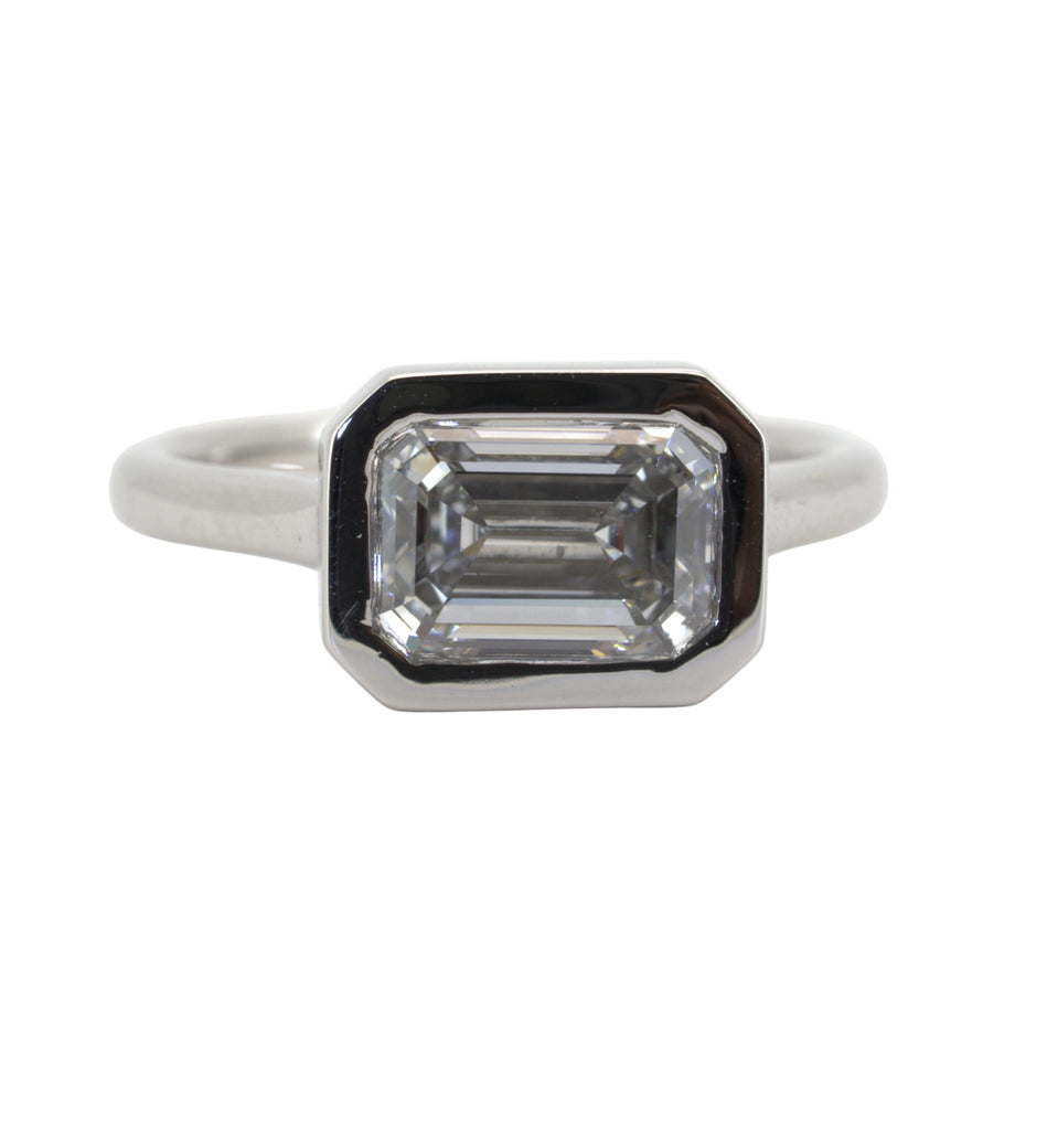 Diamond ring with emerald-cut stone on a white background